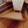 A chair with a cane seat on top of the floor.