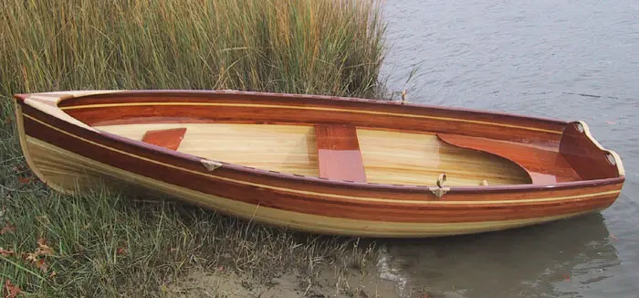 A small wooden boat sitting on the shore of a lake.