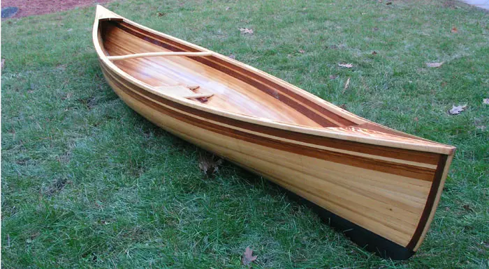 A wooden boat sitting on top of grass.