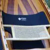 A wooden boat with a black seat and cover.