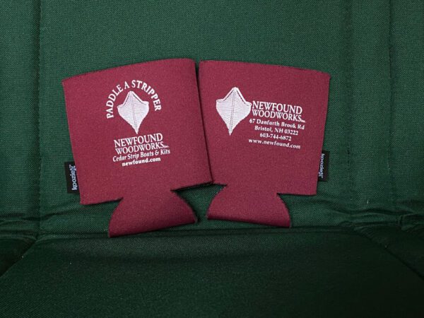 Two maroon Newfound Koozies sitting on a green chair.
