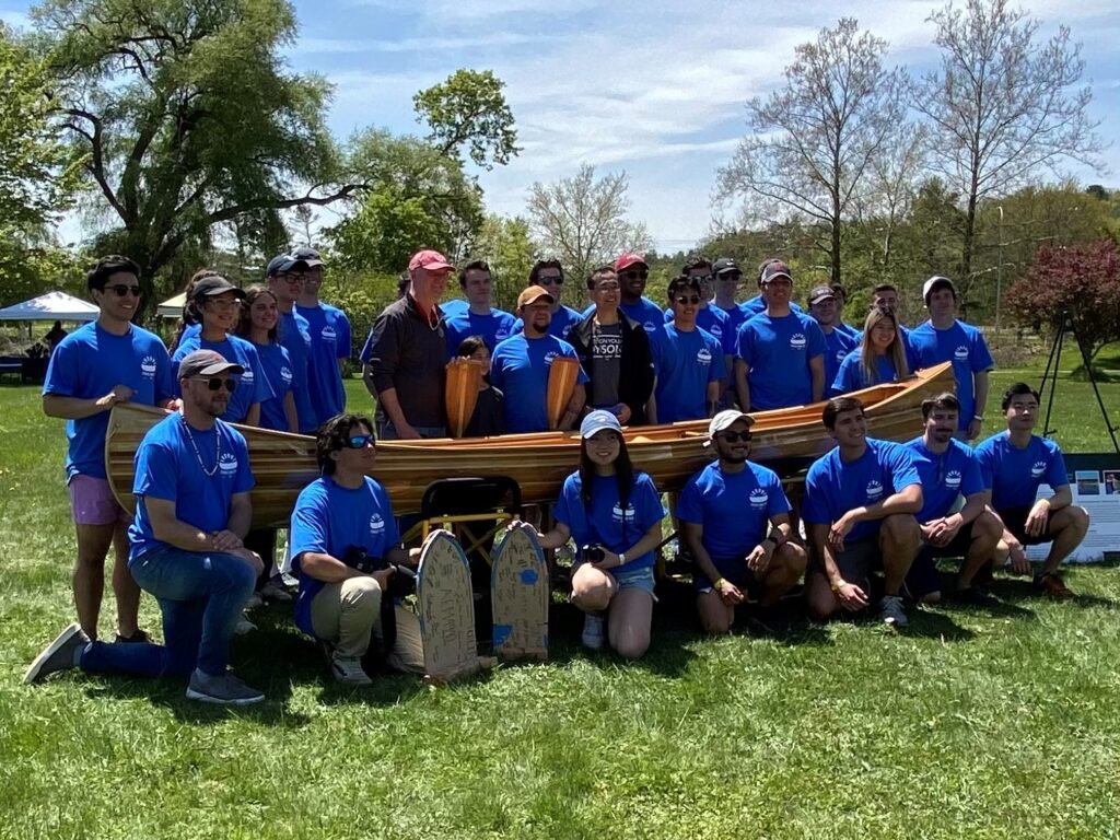A group of people posing with a canoe.