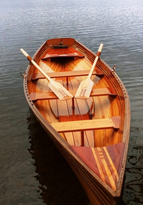 A wooden boat with two paddles on the side of it.