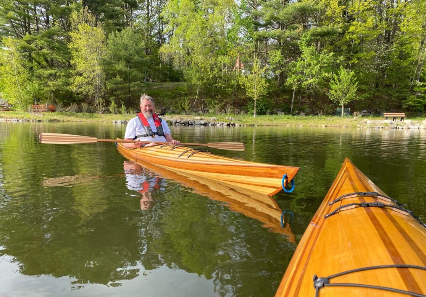 A man in red jacket holding two yellow kayaks.