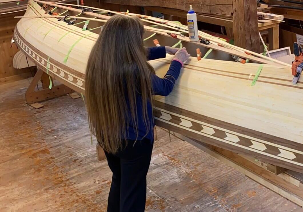 A woman standing in front of a boat.