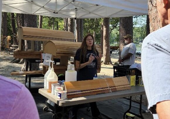 A woman standing at a table with wood.