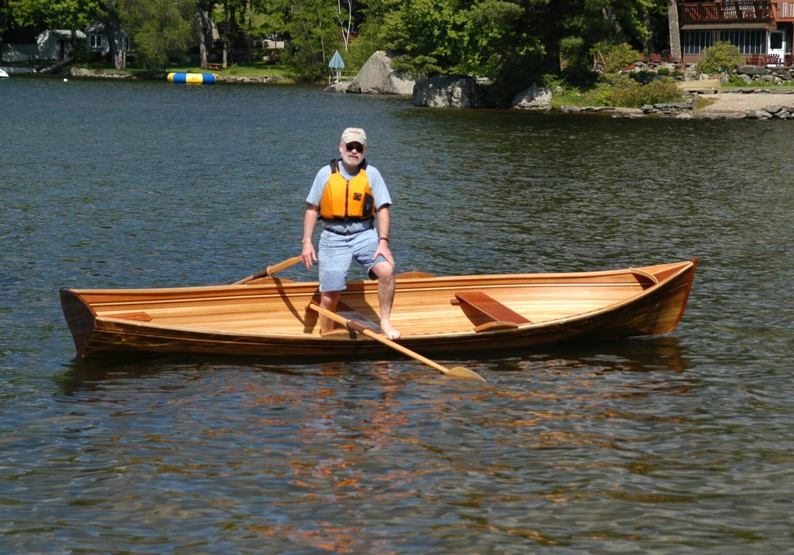 A man in blue shirt riding on the back of a boat.